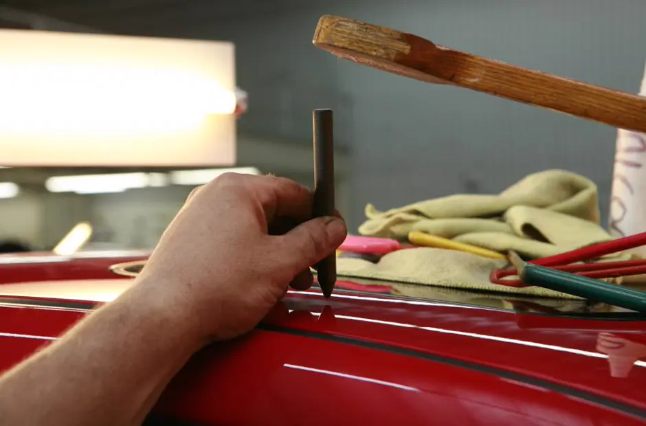 A technician's hand working on a car panel